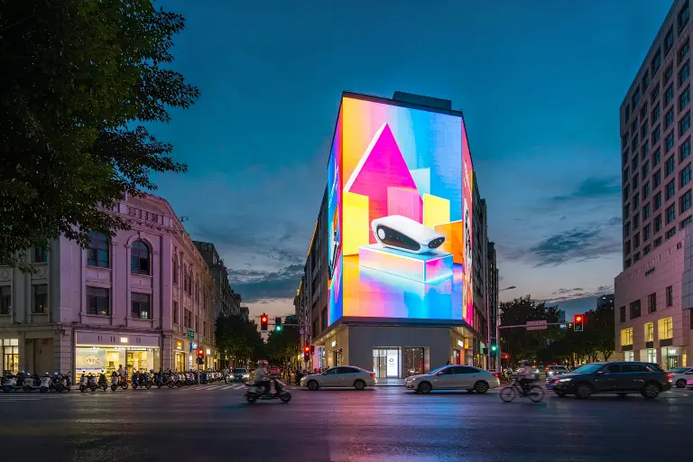Outdoor LED screen for advertising mounted on a city building facade at dusk