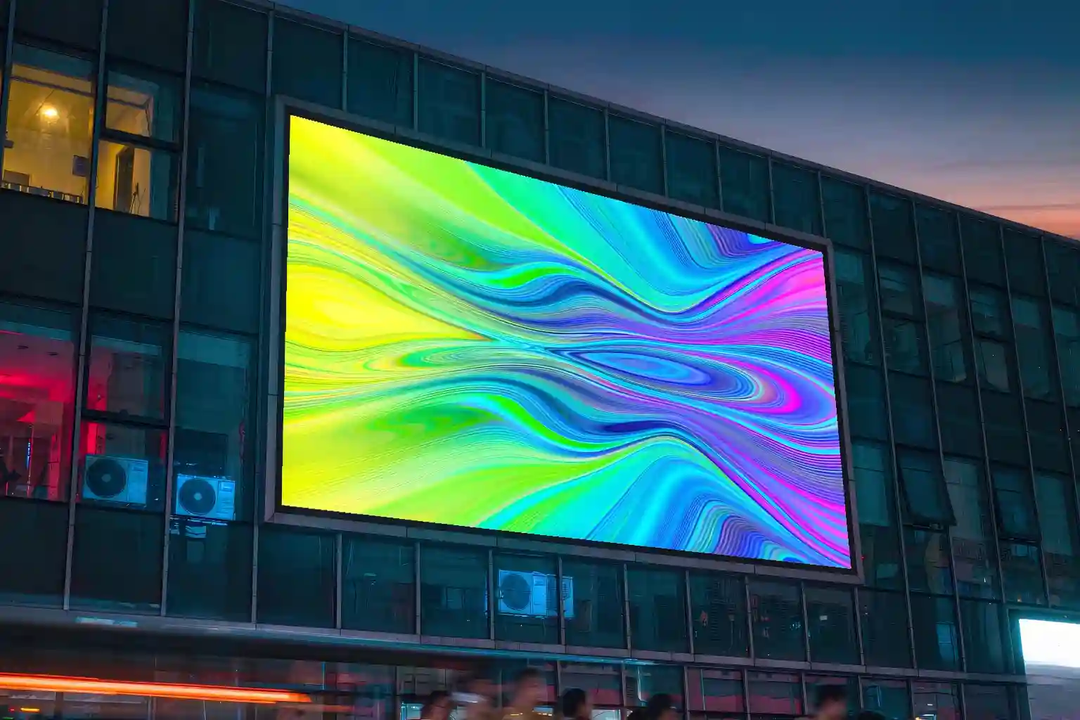 Large outdoor digital signage board on a city building facade at dusk